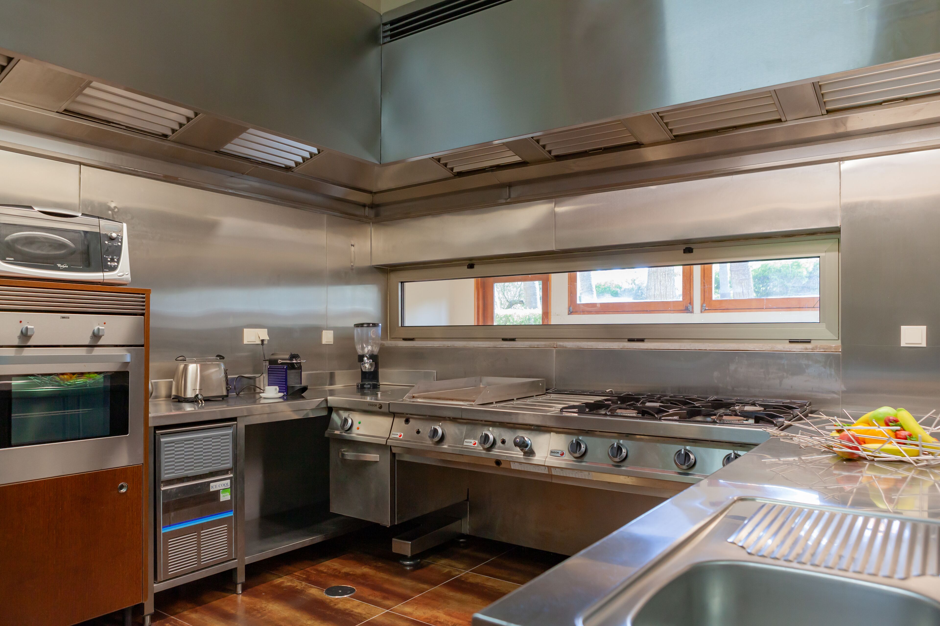 Una cocina comercial con electrodomésticos de acero inoxidable, incluyendo un microondas, horno y estufa.