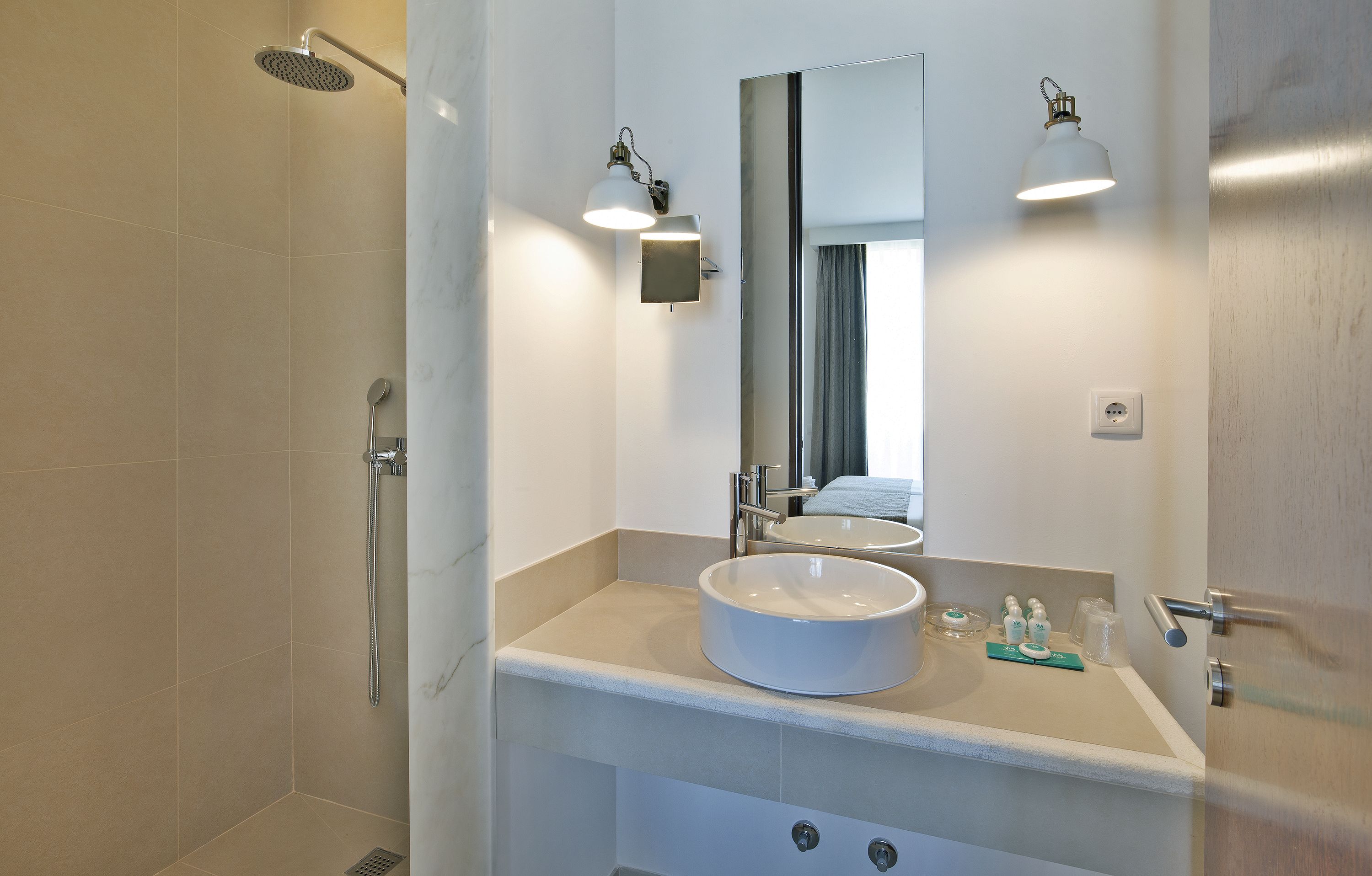 A bathroom with a large mirror, a round sink, and a shower.