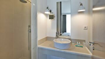 A bathroom with a large mirror, a round sink, and a shower.