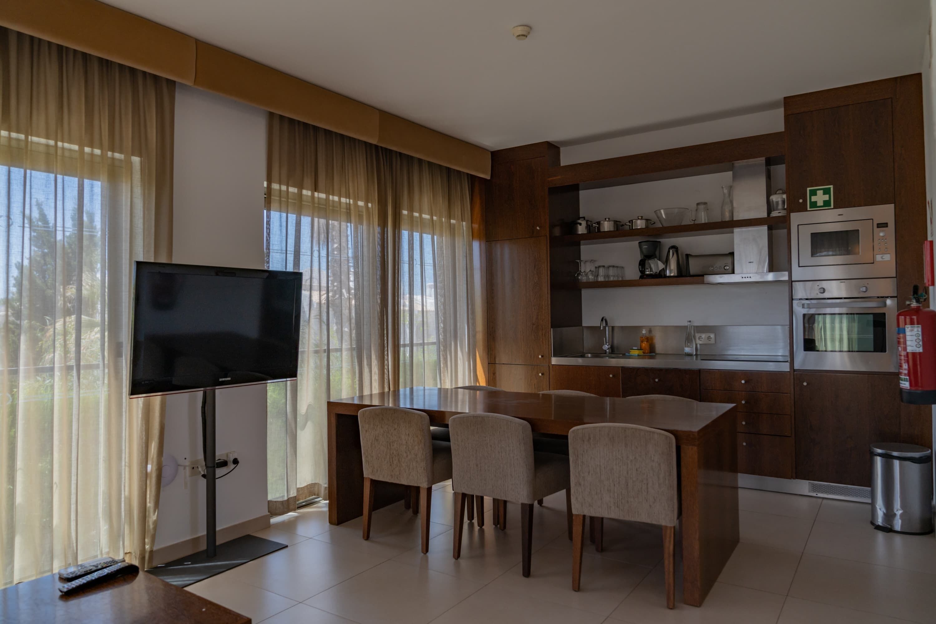 A modern kitchen with a dining area, built-in appliances, and a flat-screen TV.