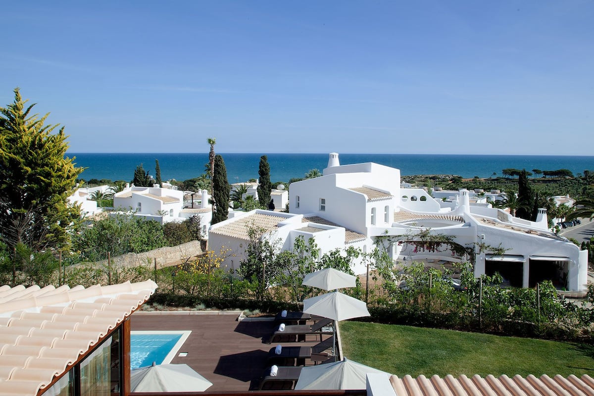 Una vila costanera amb piscina, mobiliari exterior i vista al mar.