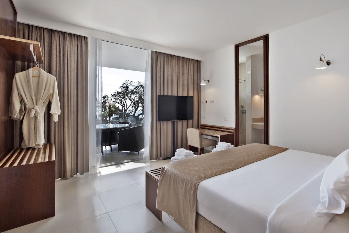 Habitació d'hotel amb llit, televisió, escriptori amb cadira, bata i vistes a l'exterior.