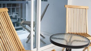 A balcony with two wooden chairs and a small round table. - Just Inn Semarang (Semarang)