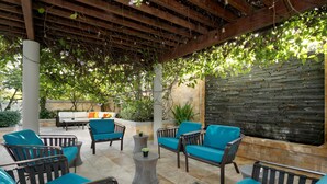 An outdoor seating area with chairs and a table, a stone wall, and a pergola structure.
