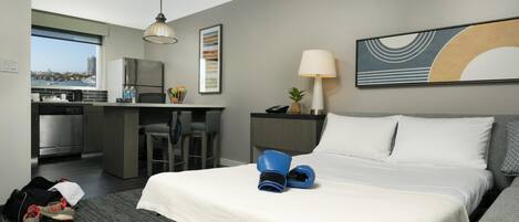 Habitación de hotel con cama, escritorio, silla, lámpara y vista a la ciudad.