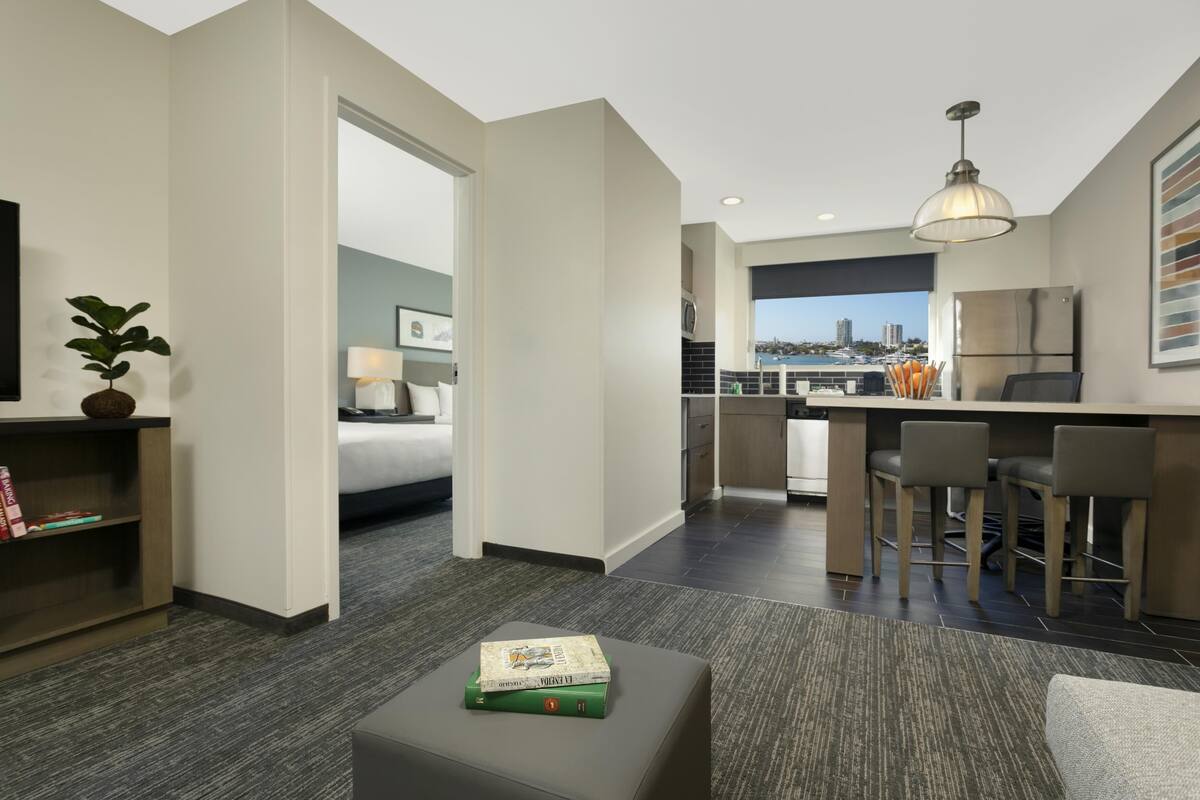 Een moderne hotelkamer met kitchenette, een eethoek, een bed en uitzicht op de stad.