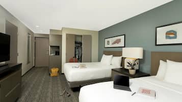 Habitación de hotel con dos camas, un televisor, un escritorio con lámpara y un armario.