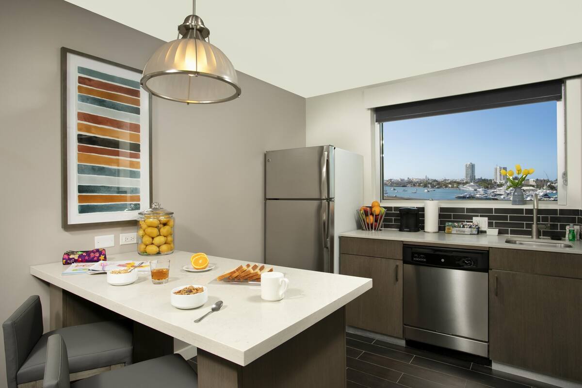 Een moderne keuken met een groot keukeneiland, roestvrijstalen apparatuur en uitzicht op de jachthaven.
