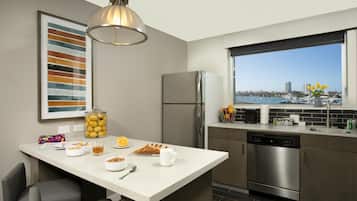Una cocina moderna con una isla grande, electrodomésticos de acero inoxidable y vista al puerto deportivo.