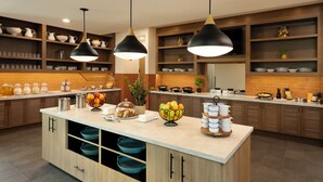 A modern kitchen with wooden cabinets, a central island, and pendant lighting.