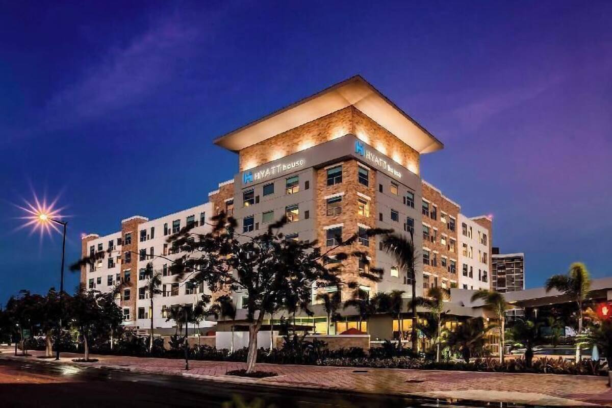 Een meerhoog hotel met een plat dak en een bord waarop 'HYATT HOUSE' staat.