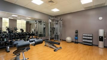 Un gimnasio con equipo de ejercicio, un espejo grande y un dispensador de agua.