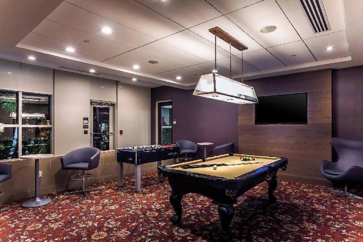 Een kamer met een pooltafel, een tafelvoetbaltafel en een bar.