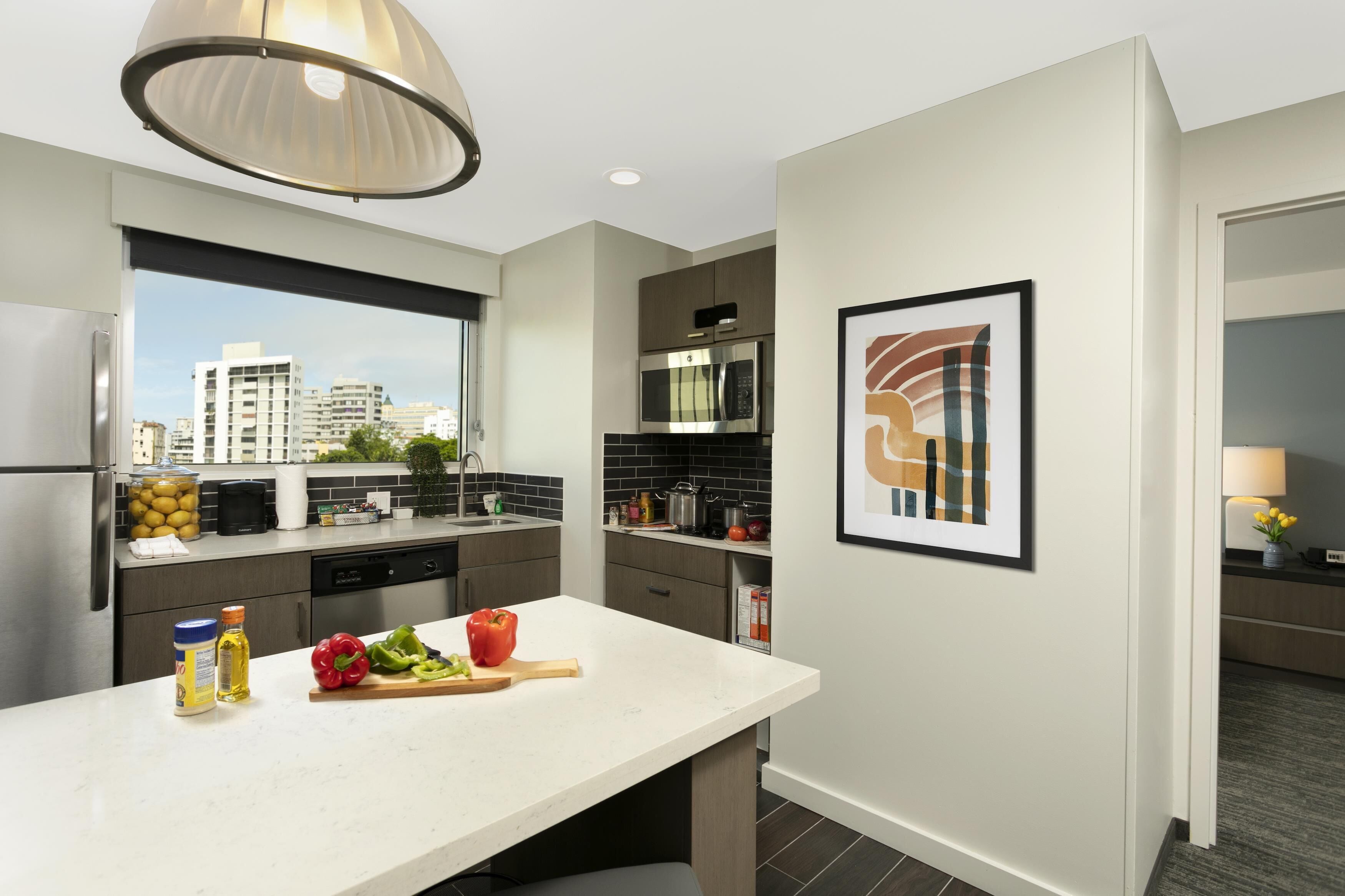 A modern kitchen with a large island, stainless steel appliances, and a city view.