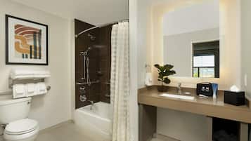 A modern bathroom with a bathtub, toilet, sink, and a shower with a curtain.