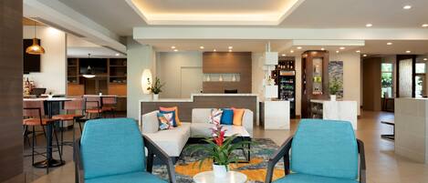 Un moderno vestíbulo de hotel con zona de estar, mostrador de recepción y bar.