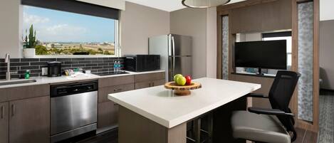 Una cocina moderna con una isla grande, electrodomésticos de acero inoxidable y vistas a la ciudad.