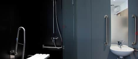 A modern bathroom with a white sink, a mirror, a shower with a handheld showerhead, and a grab bar.