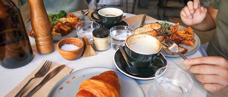 Uma mesa com croissant, café e diversos pratos, indicando um ambiente de refeição.