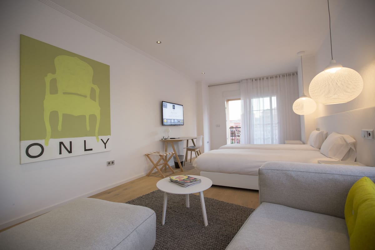 Una habitación de hotel moderna con una cama, un sofá, una mesita y un televisor.