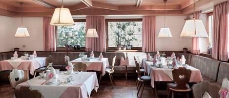 A restaurant with tables set for dining, featuring a warm color scheme and natural light from large windows.