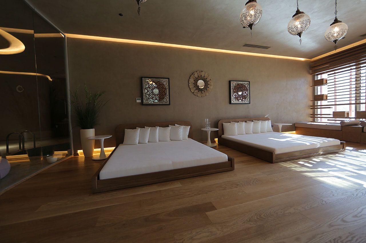 Ein modernes Schlafzimmer mit zwei Betten, einem kleinen Tisch und dekorativer Wandgestaltung.