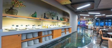 A modern restaurant with a long counter, shelves with plates, and decorative items.