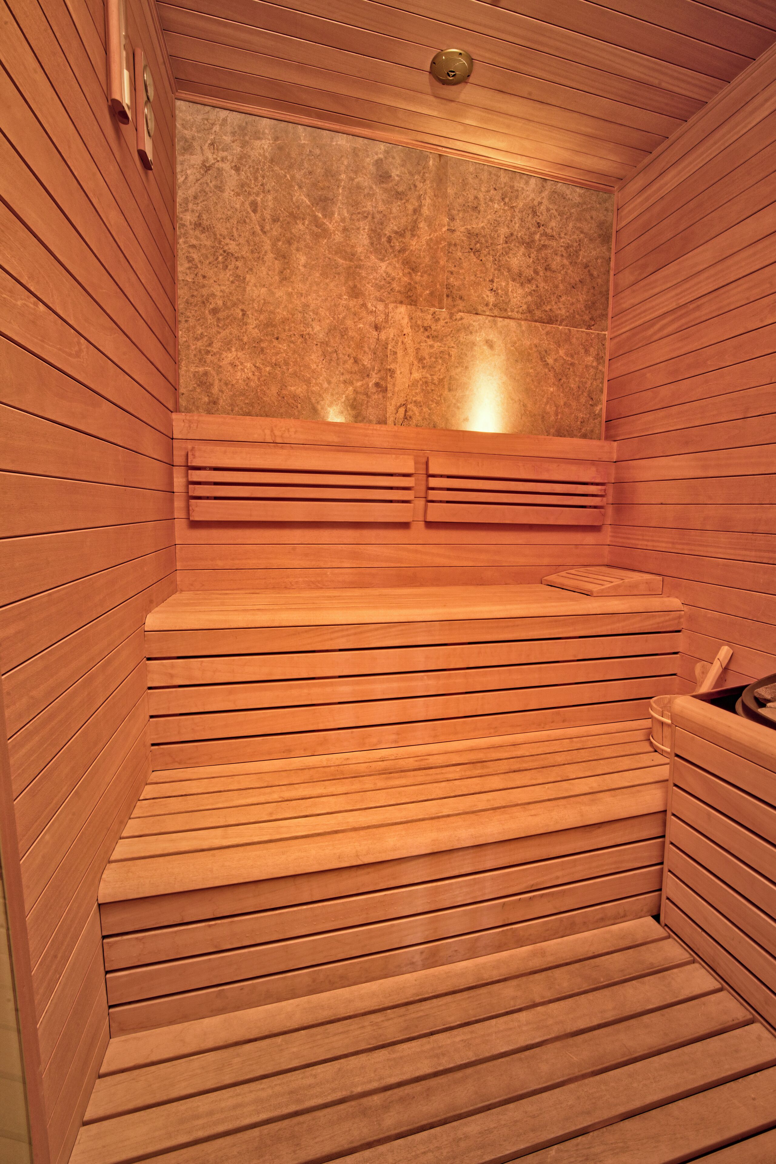 Una sauna con bancos de madera y pared de piedra.