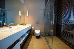 Ein modernes Badezimmer mit großem Spiegel, Waschbecken, Toilette und Duschkabine aus Glas.