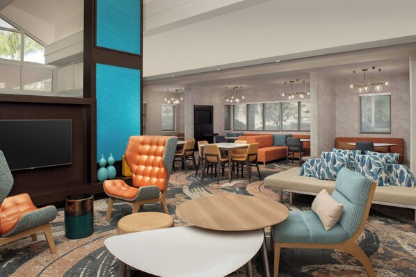 A spacious lobby with a large TV, comfortable seating areas, and a dining setup.