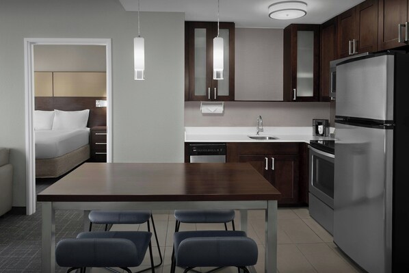 A modern kitchen with a dining table, bar stools, a refrigerator, and a dishwasher. - Residence Inn by Marriott Fort Lauderdale Airport & Cruise Port (Dania Beach)