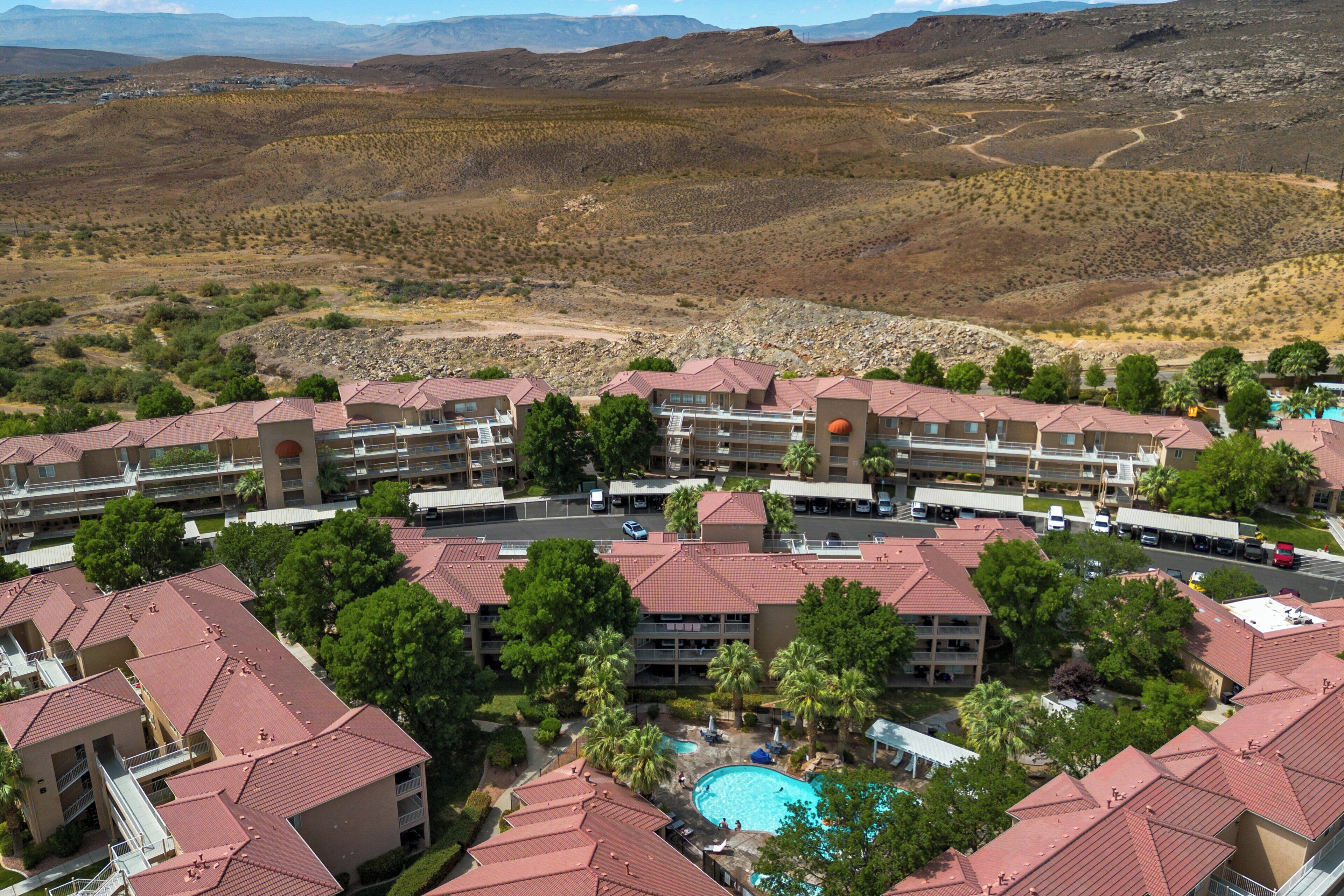 A resort with multiple buildings, a swimming pool, and a mountainous backdrop.