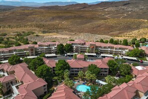 A resort with multiple buildings, a swimming pool, and a mountainous backdrop.