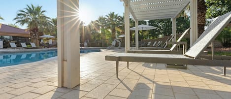 A poolside area with lounge chairs, a pergola, and a clear view of the pool.