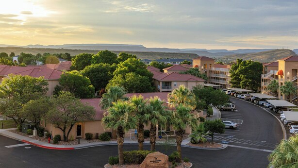 A residential area with multiple-story buildings, a parking lot, and a clear view of distant hills. - WorldMark St. George (St. George)