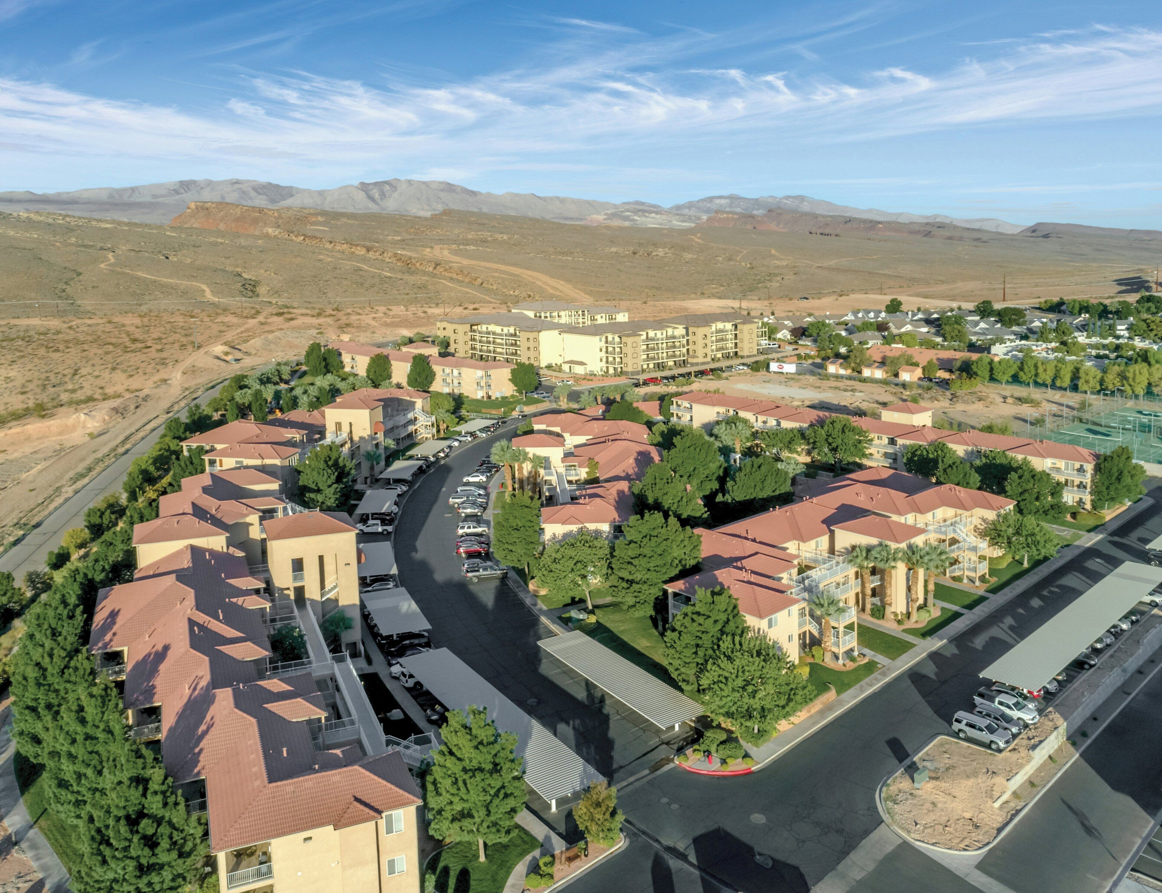 Un quartier résidentiel composé d’immeubles à plusieurs étages, de routes et bordé par un paysage montagneux.