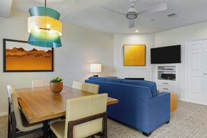 A modern living room with a wooden dining table, blue sofa, and a ceiling fan. - WorldMark St. George (St. George)