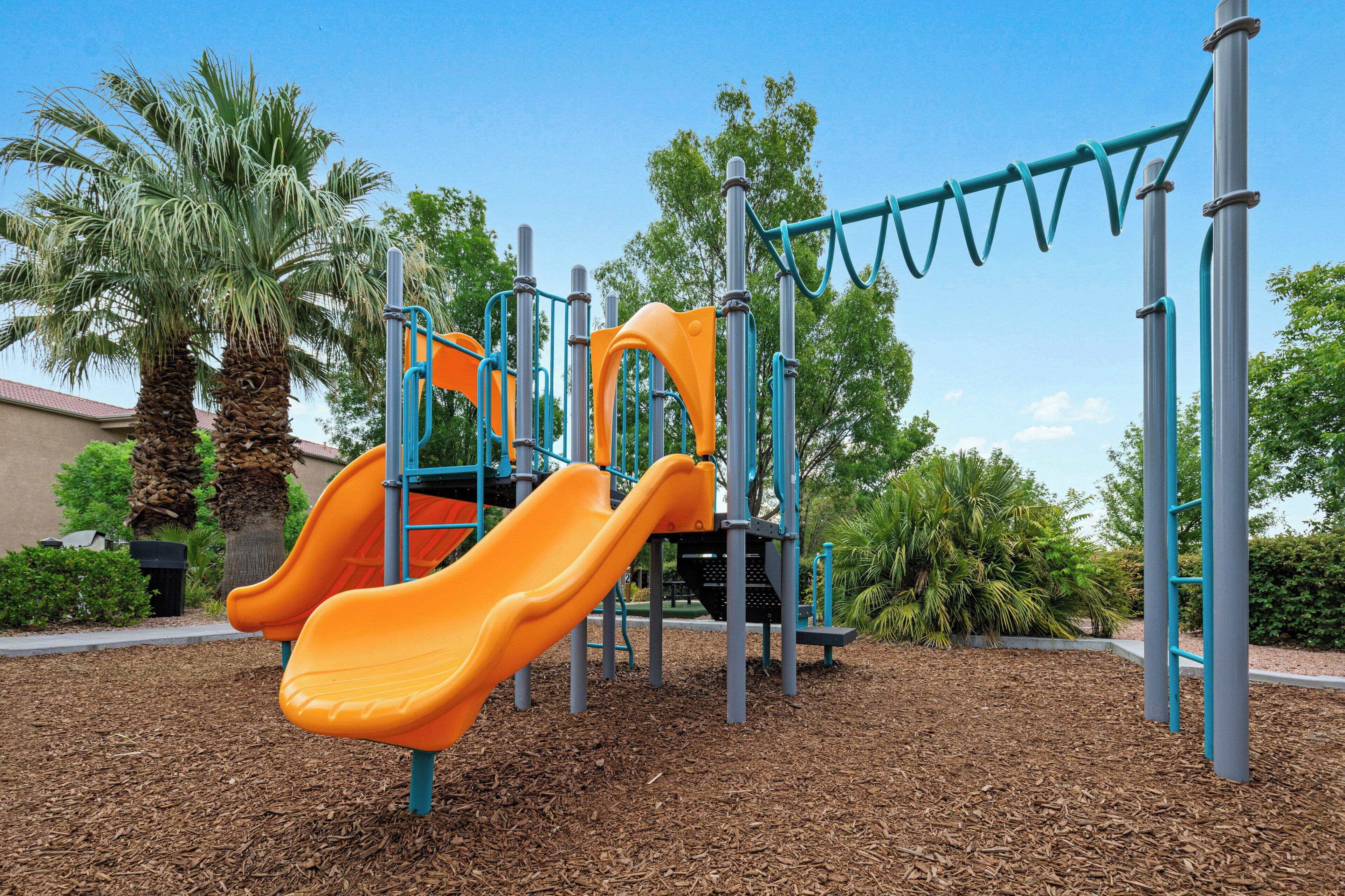 A playground with two slides and climbing structures.