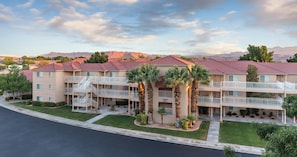 A multi-story residential building with balconies, palm trees, and a view of mountains in the background. - WorldMark St. George (St. George)