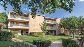 A multi-story residential building with balconies, a well-maintained lawn, and a clear sky. - WorldMark St. George (St. George)
