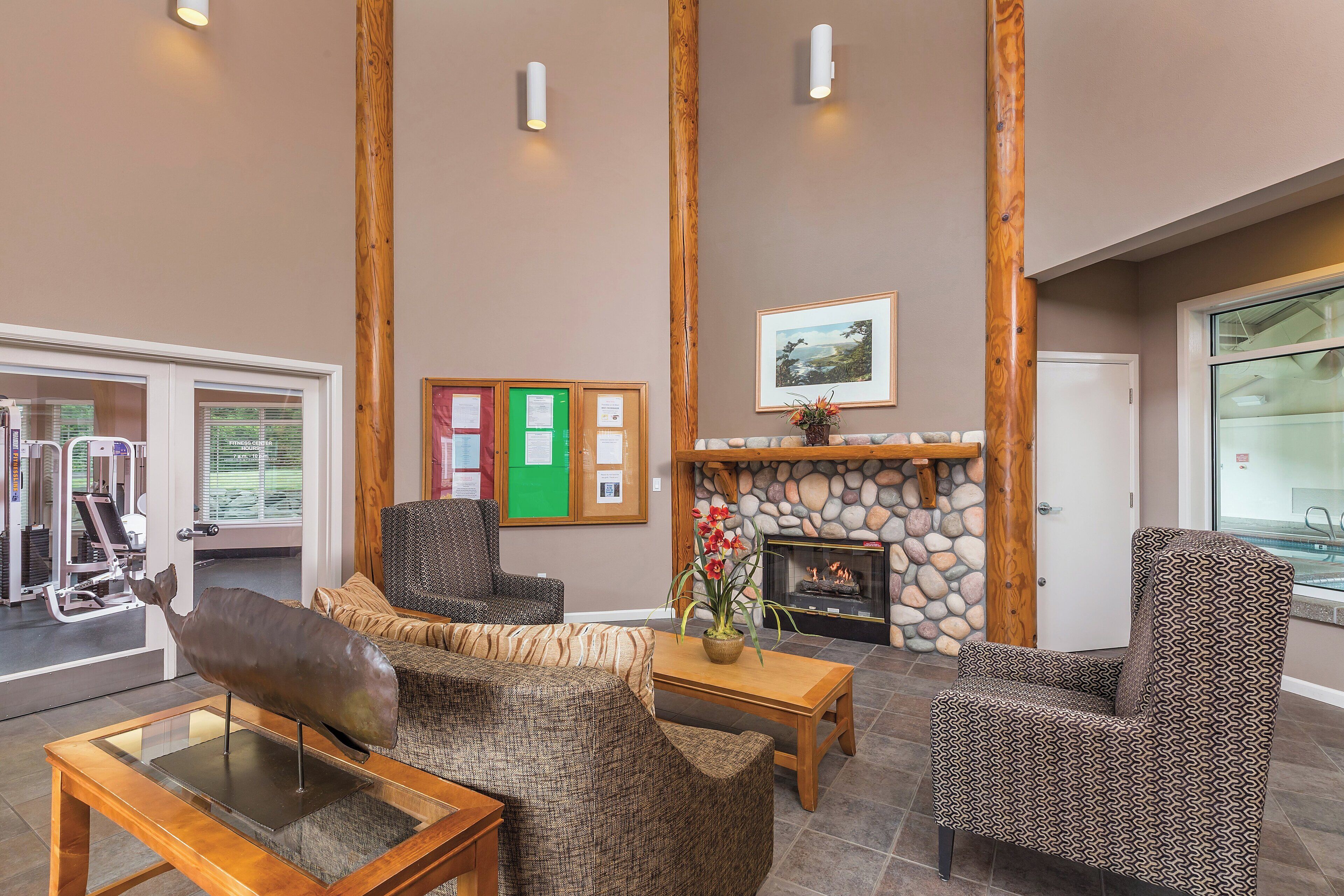 A lobby with a fireplace, seating area, and exercise equipment.