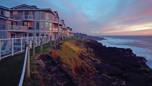 Un hotel frente al mar con varios balcones, una zona ajardinada y vistas al océano.