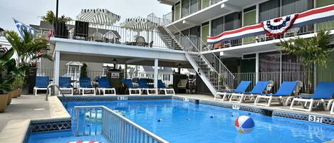 En swimmingpool med liggestole og et flag.