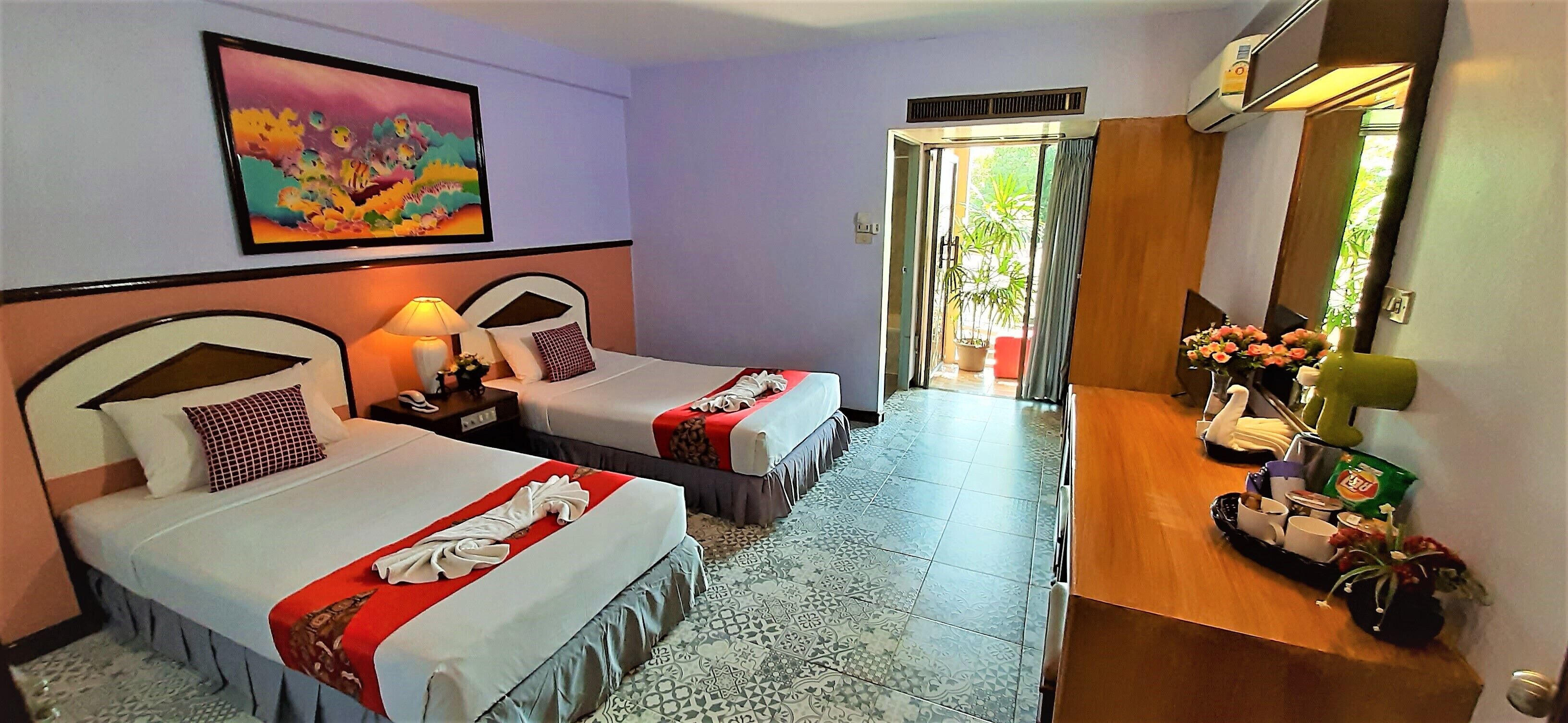 Habitación de hotel con dos camas, una zona de estar pequeña, una ventana con vistas y un cuadro en la pared.