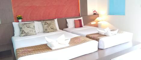 A hotel room with two beds, a red tapestry, a small plant, and a nightstand with a lamp.