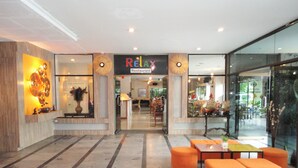 Un interior moderno con un letrero que dice 'Relax Restaurant', piso de mármol y asientos color naranja.