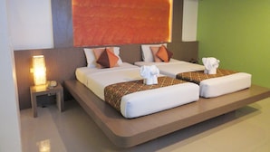 Una habitación de hotel con una cama grande, dos almohadas, una mesita de noche con una lámpara y una pared verde.