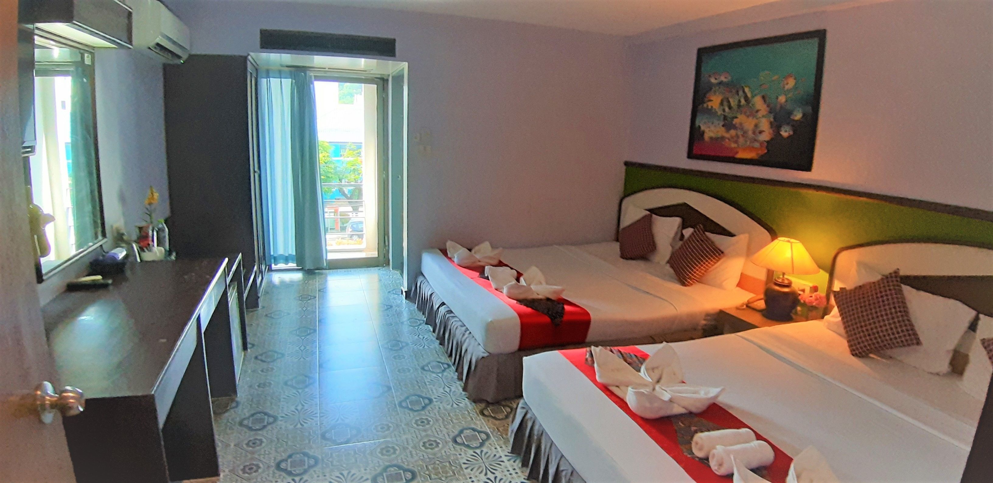 A hotel room with two beds, a desk, and a door leading to a balcony.