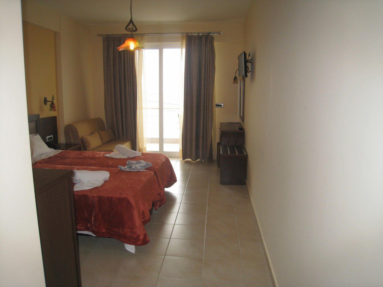 Quarto de hotel com duas camas, televisão, secretária e uma cadeira.