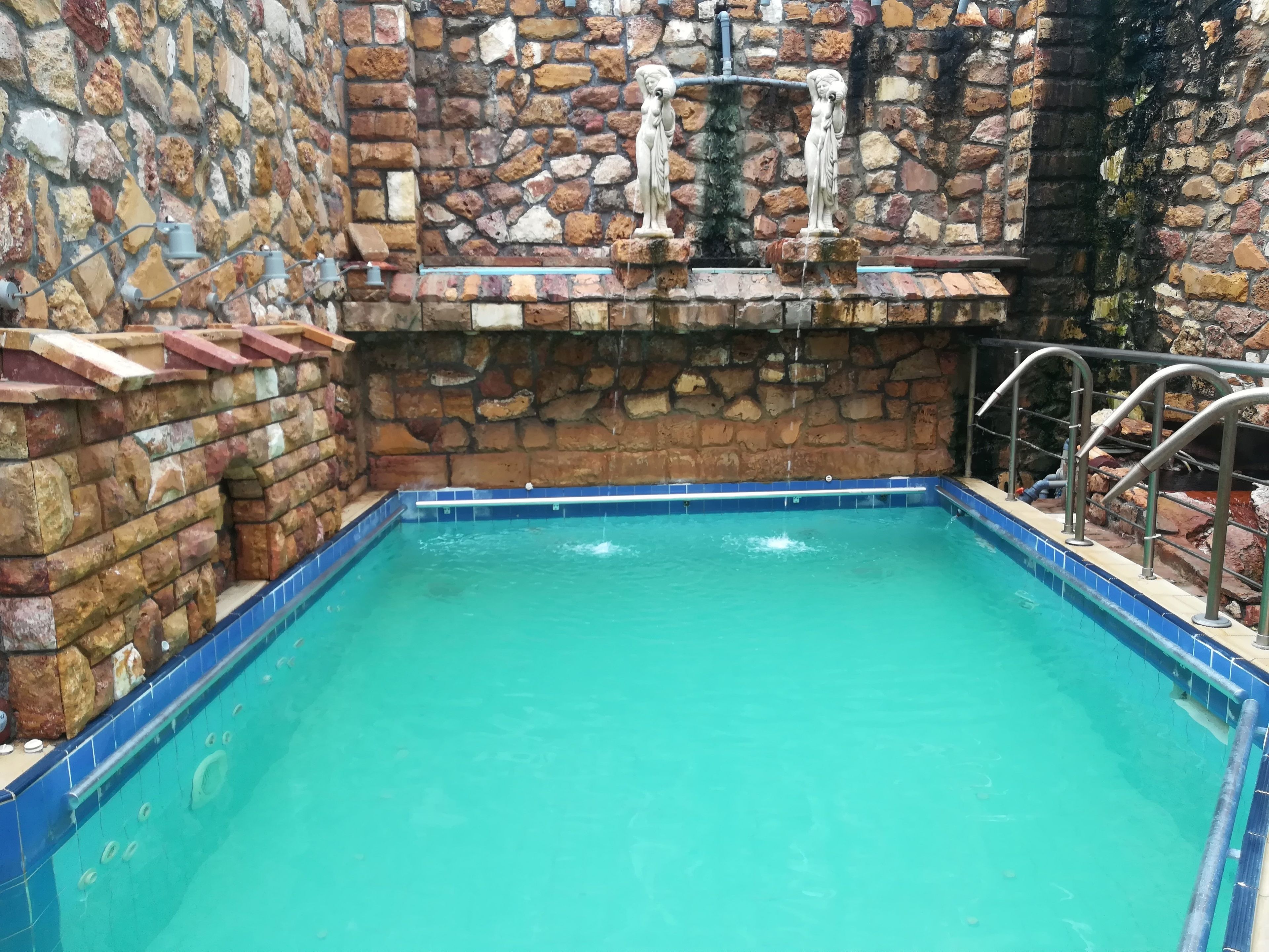 A swimming pool with stone walls and a blue tiled edge.